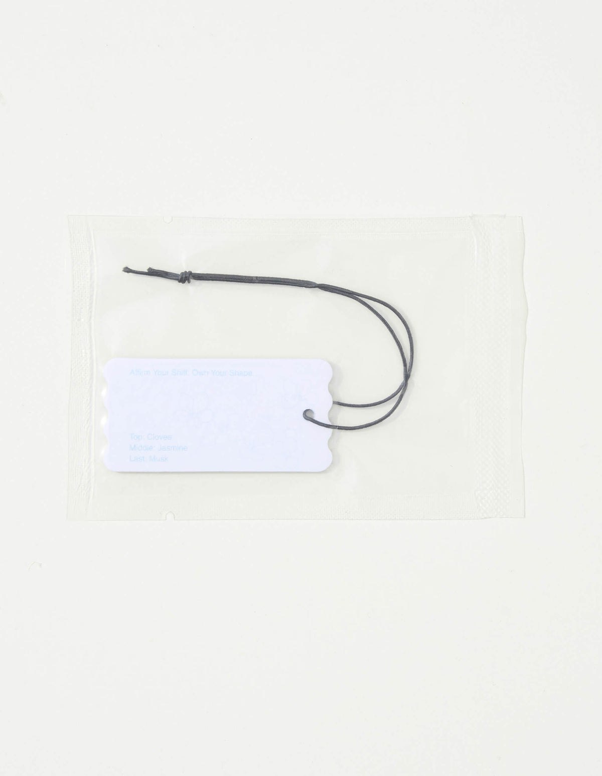 BnDR Fragrance Tag. sealed pouch with white scalloped tag showing clove jasmine musk notes. alt 01